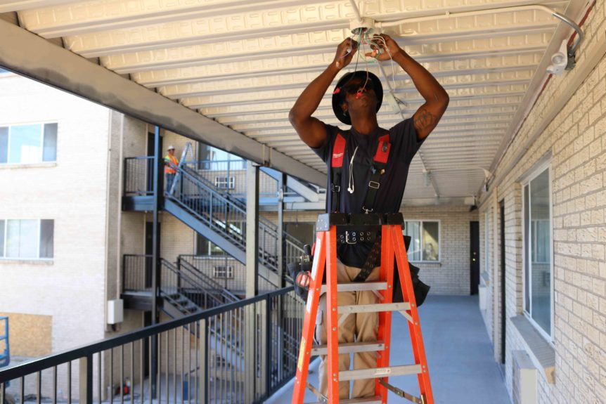 A construction worker installs high efficiency lighting at an multifamily affordable housing property
