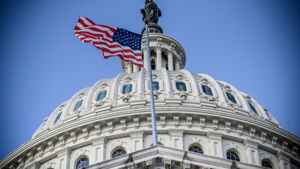 American flag flying in front of the United States Capitol building.