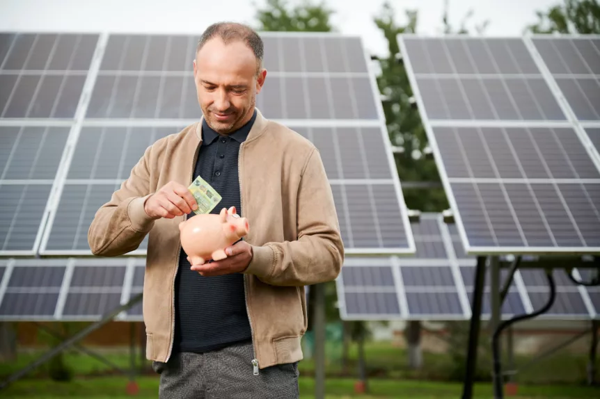 Man putting money in bank with solar panels behind him